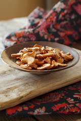 Sliced and dried Apple slices lie in a ceramic plate on a wooden plank. Vertical position, close-up.