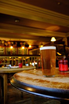 Closeup Of A Glass Of Beer On The Table Under The Lights In The Bar With A Blurred Background