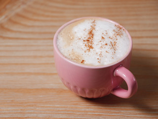 Pale pink cup of  coffee (cappuccino) on natural wood table