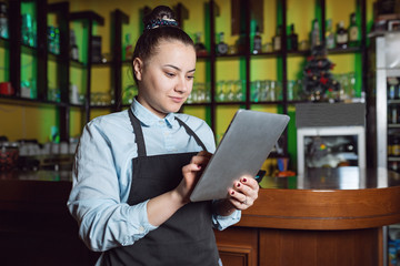 Smiling female waiter using tablet in cafe bar