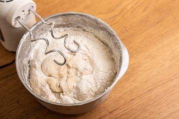 Hand mixer and a metal bowl with dough.