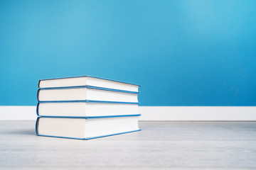 Pile stack of books on the floor or table in front of the blue wall