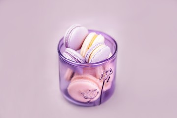 Pale purple glass with macaroons or macarons on the gray background. Glassware made of recycled glass, eco friendly concept. Copy space
