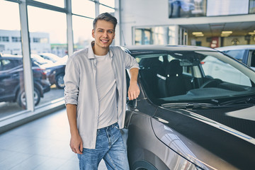 Fototapeta na wymiar Happy man rejoicing buying a new car in showroom.