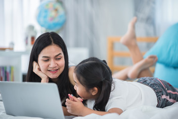 2 sisters are happily using their tablet on their beds.
