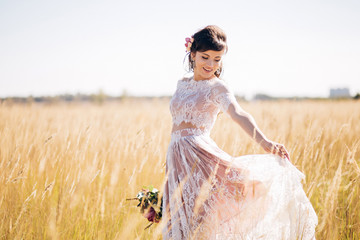 Closeup portrait of a beautiful girl in a lace dress with a bouquet of red and burgundy flowers in her hands. A young woman walks outdoors, laughs and smiles. Girl with flowers in her hair.