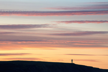 Fototapeta na wymiar Man stands on a mountain at sunset