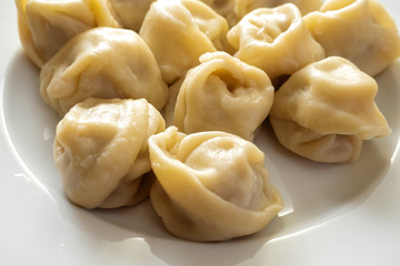 Portion of traditional Russian cooked dumplings on a white plate and wooden table, Close up.