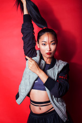 young pretty asian girl posing cheerful on red background, fashion makeup and clothers