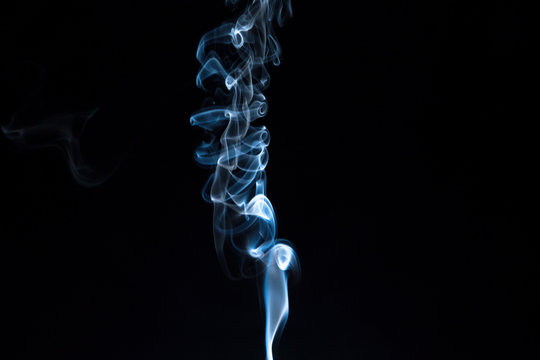 Puff of smoke from an incense stick on a dark background. Stock Photo |  Adobe Stock