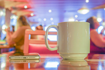 Coffee cup and cell phone on a table.