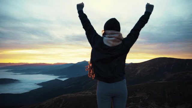 View of camera is approaching zooming woman stands on mountain top rised his hands pure nature enjoying the landscape slow motion sky clouds on the hill outdoor sunrise tourist journay