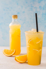 Refreshing orange lemonade in a plastic glass with slices of orange.