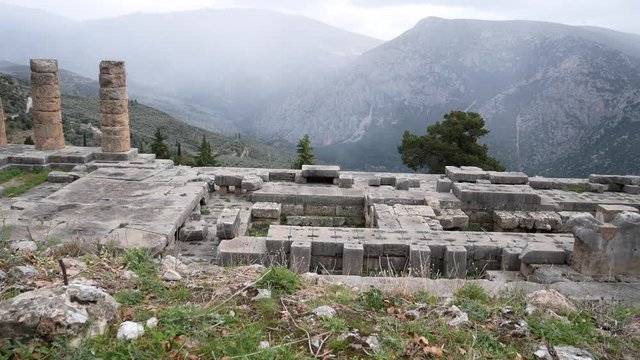 Delphi, Grece, Europe - dicember 30 2019: turists visit the ruins of the ancient temple of Apollo, archaeological site of Delphi along the slope of Mount Parnassus, UNESCO World Heritage.