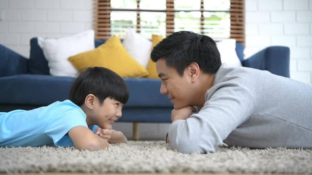 Family concept. Father and son lie down to talk on the floor of the house. 4k Resolution.