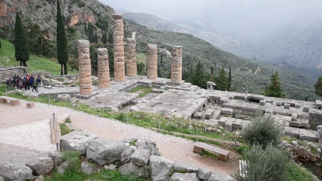Delphi, Grece, Europe - dicember 30 2019: turists visit the ruins of the ancient temple of Apollo, archaeological site of Delphi along the slope of Mount Parnassus, UNESCO World Heritage, Greece.