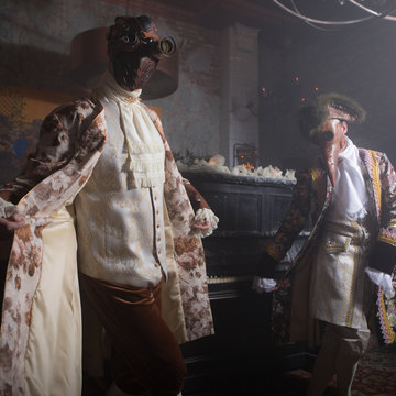 Actors in Steam punk masks and antique costumes indoor.