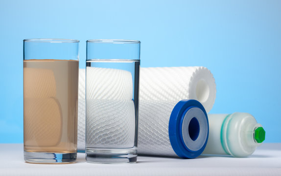 Glasses of dirty and clear water and filter cartridges
