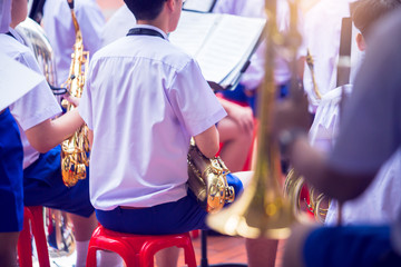 Selective focus to saxophone in the musician's hand. The musician's hand is holding the saxophone, ready to play in the orchestra band.   Thai student. © Koonsiri