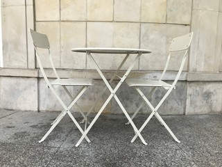 Uroczy stolik z dwoma krzesłami na tle beżowej ściany z kamienia