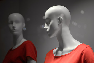 Two white mannequins in red T-shirts on a grey background