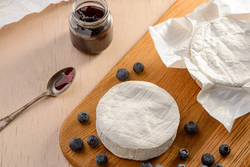 Camembert cheese, blueberries and jam on a kitchen table