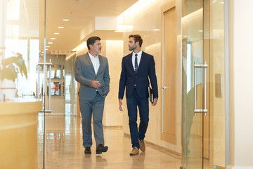 Fototapeta na wymiar Mature businessman walking and talking with young colleague