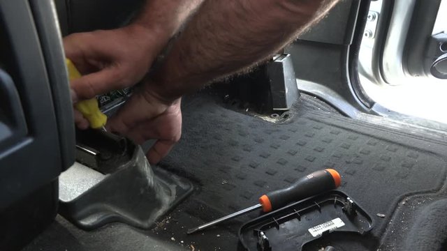 Dismantling unscrewing the vehicle seat. Car seat fixed to the floor. A worker is trying to dismantle the car seat. Professional master socket set ring spanner turnscrew screwdriver work hand working.