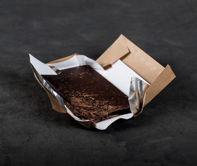 Bitter dark chocolate on a wrapper on a dark background