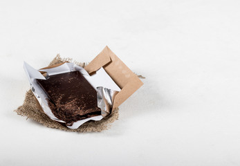 Bitter dark chocolate on a wrapper on a light background