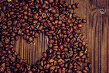 An abstract depiction of love for coffee. The heart of coffee beans on a wooden background. Top view.