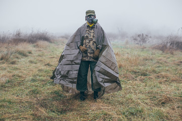 soldier in field wearing gas mask and chemical weapons protection clothing