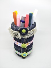Fototapeta na wymiar Handmade craft recycle bottle and jeans become pencil stationary case desk. Tube box shape with top hole. Decoration with sand, button and bordir embroidery. Work process cut sewn taped glued dry. 