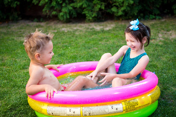 Kids having fun party swimming in back yard pool. Funny children bathing in the outdoor pool. Happy children playing in the water. babies Having Fun In Garden Paddling Pool