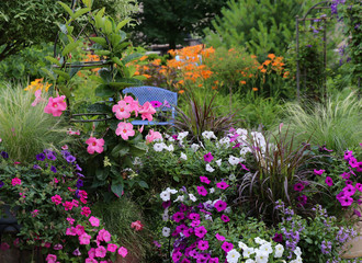A blue metal bench is focal point of this Gardenscape incorporating flowers that are hot pink, fuchsia, oranges