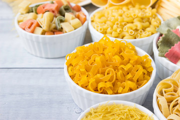 Different of types and shapes of dry Italian  of pasta on a wooden table.