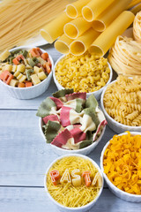 Different of types and shapes of dry Italian  of pasta on a wooden table.