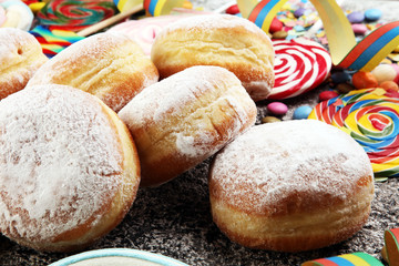 Carnival powdered sugar raised donuts with paper streamers. German berliner or krapfen for carnival - obrazy, fototapety, plakaty