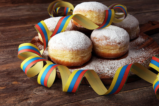 Carnival powdered sugar raised donuts with paper streamers. German berliner or krapfen for carnival