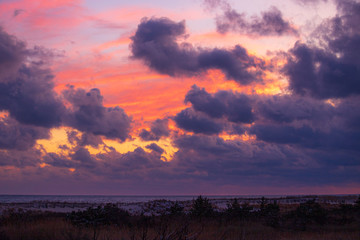 Obraz premium Vibrant sunset colors within ominous storm clouds moving over a beach. Long Island New York 
