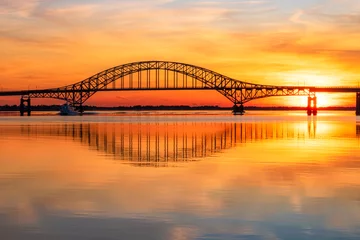 Fotobehang Stalen boogbrug over een baai met kristalheldere reflecties in het water bij zonsondergang. Fire Island Inlet Bridge, onderdeel van de Robert Moses Causeway op Long Island New York. © Scott Heaney