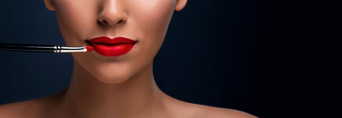 Close up of red mat lips with cosmetic brush. Professional makeup.