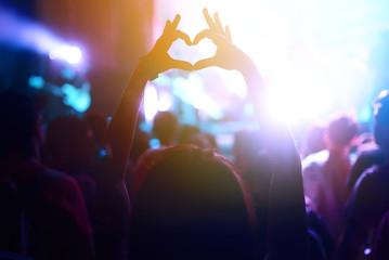 Heart shaped hands at concert, loving the artist and the festival. Audience with hands raised at a...