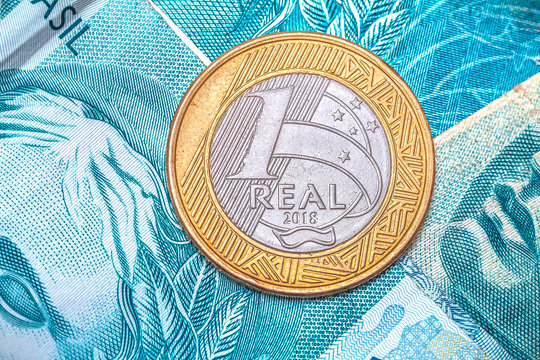 Brazilian Real - Money from Brazil. A 1 Real coin on a Brazilian Real banknotes of 100 reais in close-up photo. Brazilian economy and finances.