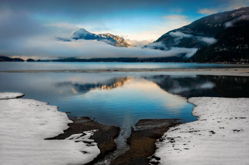 Harrison Lake Winter Landscape. Low clouds, ground fog and a small patch of blue sky are reflected in Harrison Lake in western British Columbia, Canada.
