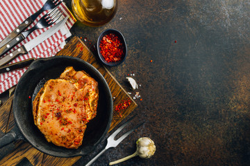 Marinated raw pork steaks on iron. Ready to cook. Dark photo. Top view.