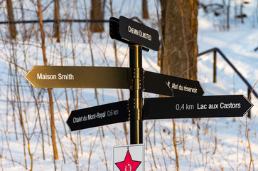Directional sign post at mount royal park Montreal pointing to places in the park snowy background 