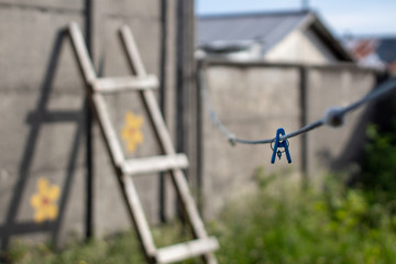 escalera apoyada en muro con cordel azúl en tendedero de ropa 