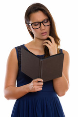 Studio shot of young beautiful woman reading book while thinking