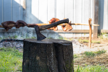 hacha clavada en un tronco con un fondo de asado 
